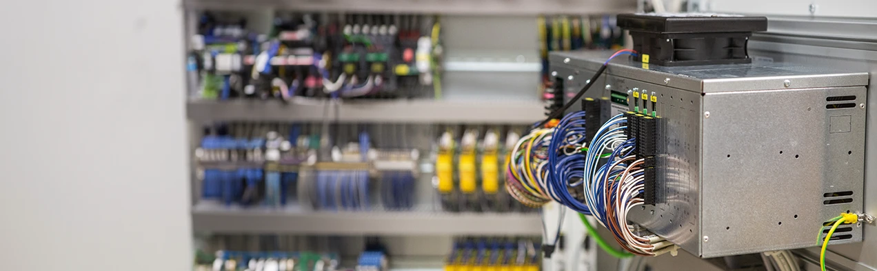 This image shows a wired industrial PC, mounted in a metal casing within a control cabinet, illustrating Cloos Electronic's manufacturing expertise in device construction. The PC, electronic cards, and wiring harnesses are all manufactured at Cloos Electronic.