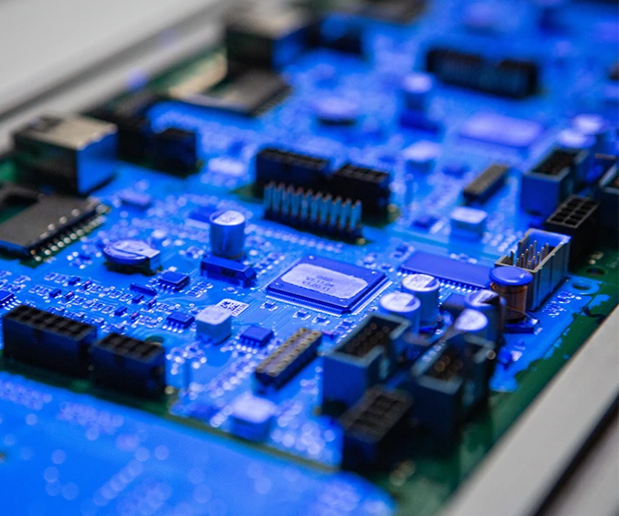 UV inspection of conformal coated electronic cards equipped with SMD and THT for quality control. After SMD assembly, the cards are coated in the selective coating machine and checked on the output conveyor.