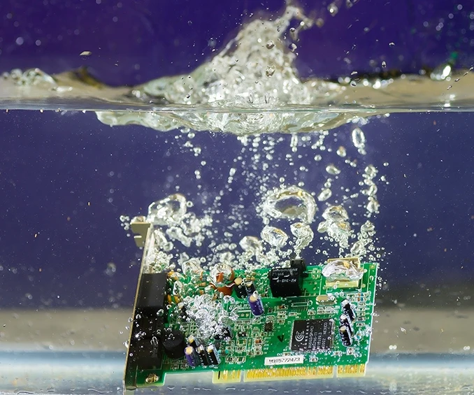 Photo of an SMD electronic board from CLOOS electronic, surrounded by water, to demonstrate the protective effect of the Parylene coating. This image impressively illustrates how the coating protects the electronic components from moisture, ensuring reliability and durability in demanding environments.