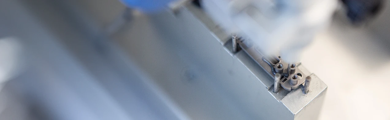 This image shows an automatic glue dispenser applying adhesive to a precision mechanism, illustrating advanced automation technology in mechanical assembly at Cloos Electronic. This process enhances precision and efficiency in manufacturing.