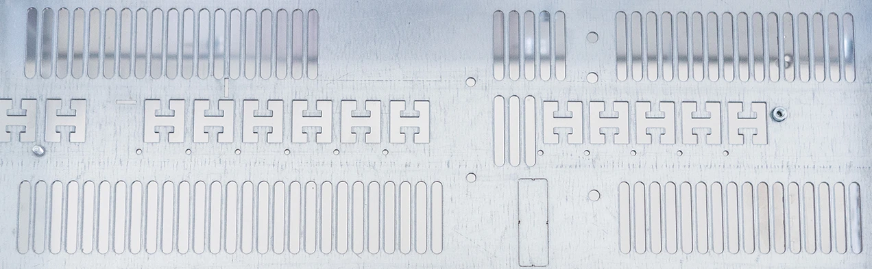 The image displays a sheet metal with precise cutouts, used in the production of device enclosures. It exemplifies the qualified supplier network of Cloos Electronic for the procurement and processing of sheet metal parts.